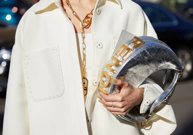 woman,color,bag,illustrative editorial,milan,gold,outfit,influencer,white,street,fendi,golden,logo,sunny,elegant,editorial,jacket,necklace,look,people,outdoor,stylish,sunlight,luxury,silver,style,accessory,colorful,photography,fashion finger hand person clothing coat helmet long sleeve sleeve jewelry necklace