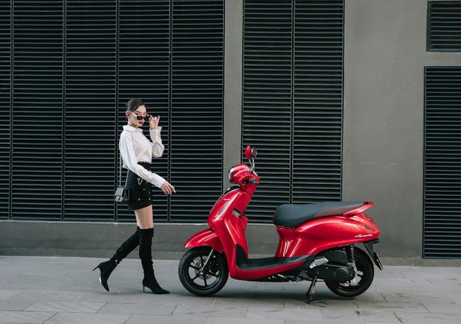scooter vehicle high heel shoe bag handbag person wheel motorcycle coat